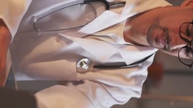 Vertical video. Doctor dissertation. Working man. Science research. Handsome inspired guy typing laptop sitting work desk light shadow room interior blur.