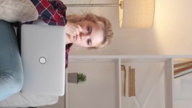 Vertical video. Inspired relationship. Happy couple. Internet support. Handsome man in headphones helping woman to working laptop light room interior.