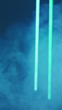 Vertical video. Color smoke. Blur glow. Fluorescent flare. Defocused neon green cyan blue light vapor floating on dark abstract free space background.