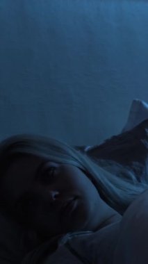 Gece endişesi. Uyku bozukluğu. Uykusuzluk hüsranı. Panik atak. Huzursuz, sinirli, deli bir kadın karanlık bir yatak odasında geç saatlere kadar ayakta kalıyor. Dikey video.