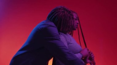 Supportive relationship. Beloved couple. Neon light portrait. Kind black man embracing sad woman to calm down on red blue background.