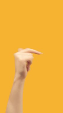 Vertical video. Hand pointing. Next page. Demonstrating gesture. Female finger sign showing right on orange copy space promotional background.