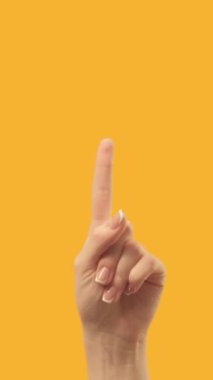 Vertical video. Advertising gesture. Special offer. Female hand finger pointing up at bright orange copy space commercial background.