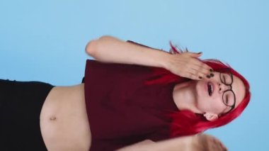 Vertical video. Air kiss. Love admiration. Romantic message. Happy girl peeking out blowing smooch on blue background seamless loop.