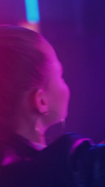 夜のリズム 踊る女性 パーティーの時間だ 紫のネオンでナイトクラブダンスを楽しんでいる無名の女性 垂直ビデオ — ストック動画