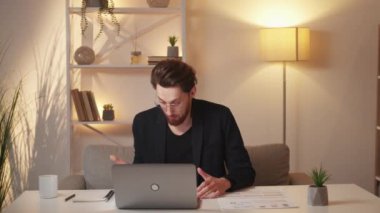 Wrong report. Male analytics. Bad work. Skeptic displeased man feeling shock checking documents looking laptop sitting light room interior.
