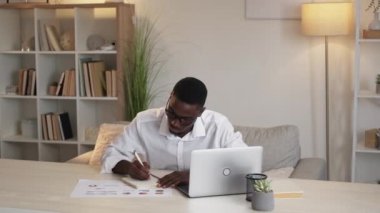 Business analytics. Financial report. Sales strategy. Serious hardworking man working on stock market graphs making notes sitting office desk.