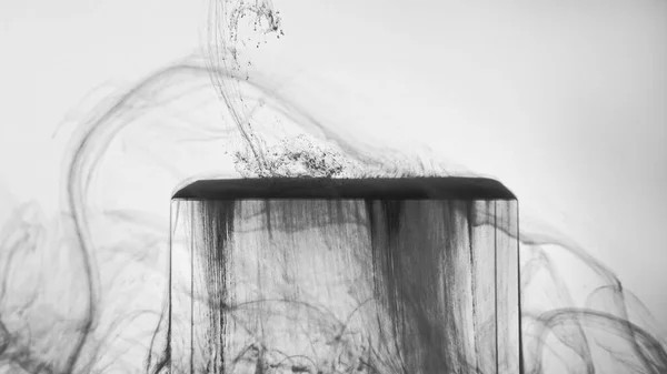 Black fume glass cube. Ink water. Fluid splash. Defocused gray smoke floating over ice edge on white grunge monochrome abstract background.