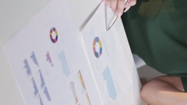 Vertical video. Data analytics. Income charts. Financial strategy. Paperwork management. Unrecognizable woman accountant working on statistics research with graphs.