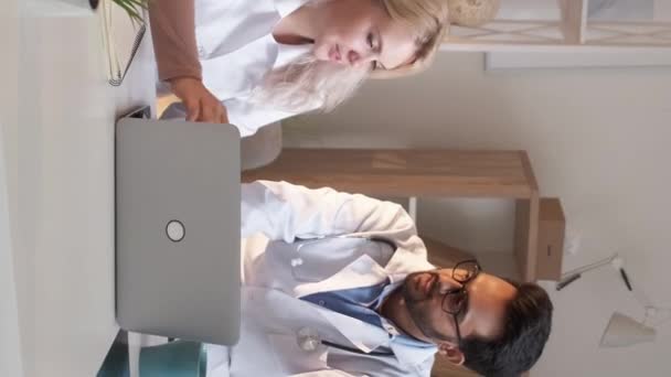 垂直ビデオ 医療関係者 研究情報 友好的なコミュニケーション 笑顔男と女を見ますラップトップの話で光の部屋のインテリア — ストック動画