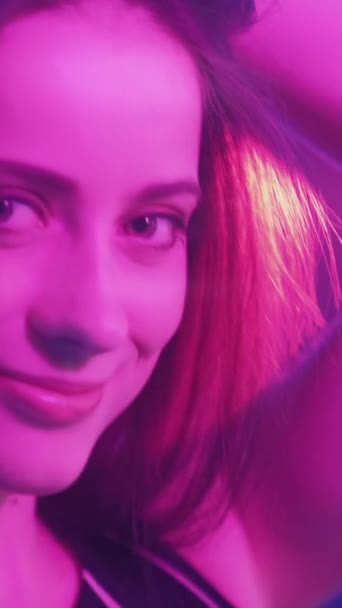 ネオンの肖像画 可愛い女だな 女性の美しさ ピンクの照明で幸せな笑顔の女性 垂直ビデオ — ストック動画