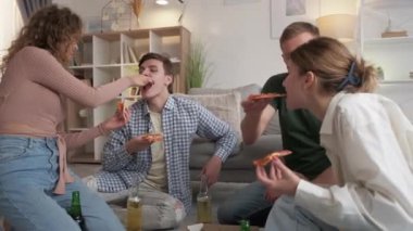 Delicious fast food. Happy friends. Students life. Cheerful men and women enjoying time together eating pizza drinking beer light room interior.