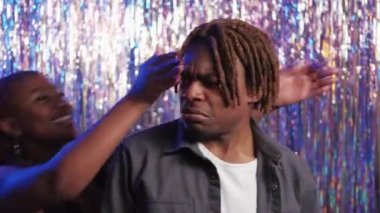 Romantic love. Beloved couple. Surprised meeting. Happy black woman closing eyes to man embracing together with pleasure on shimmering cascade curtain background.