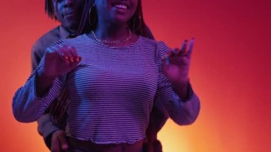 Sexy dance. Beloved couple. Neon light portrait. Positive happy black man and woman moving on music together on red blue background.