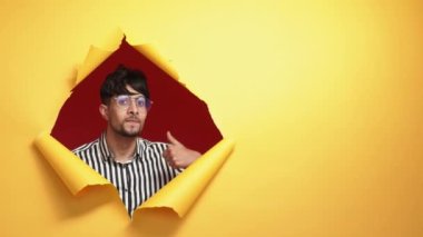 Like gesture. Perfect choice. Approval yes. Satisfied joyful man recommending showing thumb up in yellow breakthrough hole ripped paper wall on advertising copy space background.