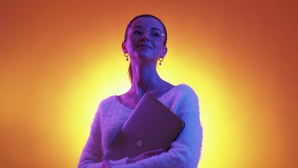 インスピレーションを受けた女性 デジタルライフ ネオンの肖像画 幸せな満足女性保持ラップトップポーズ上の紫オレンジ色の背景 — ストック動画