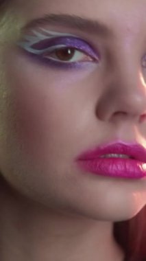 Vertical video. 90s makeup. Retro look. 2000s fashion. Closeup portrait of teen girl face with purple color eyeshadow pink lips artistic visage.
