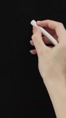 Vertical video. Target design. Creative goal. Female hand drawing white dart aim circles with center point on black chalkboard.