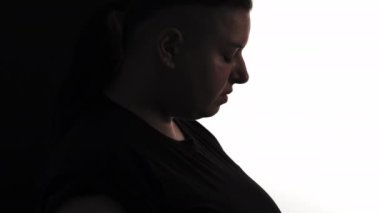 Depressed obesity. Female portrait. Body acceptance. Sad plus size silhouette profile woman posing divided black white background copy space.