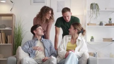 Happy friends. Inspired communication. Home meeting. Smiling men and women enjoying talk together in light room interior.