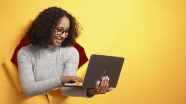Digital people. Online e-learning. Internet education. Smiling smart girl using laptop in orange breakthrough torn paper hole copy space background.