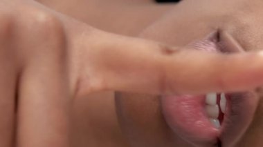 Vertical video. Shush gesture. Secret sign. Quiet woman. Cropped female portrait holding finger at lips in silence symbol.