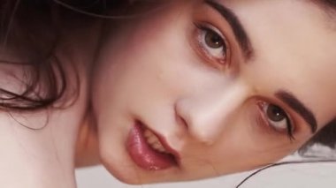 Vertical video. Natural female beauty. Fashion model shooting. Perfect skin. Smiling sensual brunette woman posing on neutral blur slow motion.