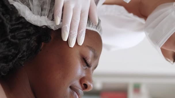 垂直ビデオ 美容室 女性患者 スキンケアチェック 皮膚科医勉強肌の笑顔の女性は軽い診療室でソファを敷設 — ストック動画