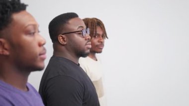 Happy friends. Hipster black men. Model shooting. Smiling guys staying in line looking camera posing light background defocused.