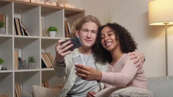 携帯のセルフィー 幸せなカップル デジタル中毒だ 光の部屋のインテリアで個人的なスマートフォンで写真を撮る愛する男性と女性にインスピレーションを与えた — ストック動画