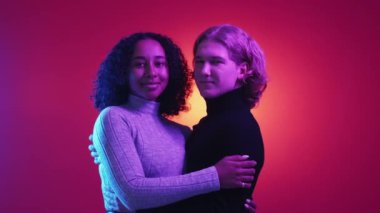 Çeşitli çiftler. Ahenkli ilişki. Neon ışıklı portre. Mutlu adam ve kadın, mor arka planda sarılıyorlar..