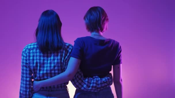 信頼できる友情だ ネオンライトの人々 女性カップル 幸せな二人の女性を受け入れます一緒に背景色上の緑紫色の背景 — ストック動画