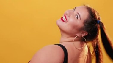 Vücut pozitif. Mutlu şişman kadın. Model çekimi. Tişörtlü neşeli, iri yarı kadın göz kırpıyor kameraya öpücük yolluyor..