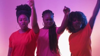 Female protest. Black lives matter. Neon light portrait. Angry three women knocking invisible barrier announcing objection on purple yellow background.