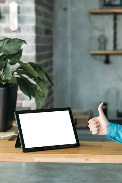 Like gesture. Computer mockup. Online meeting. Unrecognizable woman showing thumb up to tablet computer with blank screen in light room interior.