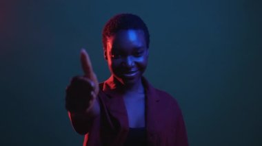 Olumlu geri bildirim. Jest gibi. Cesaret desteği. Kırmızı mavi neon rengi, mutlu bir kadın. Baş parmağıyla tavsiye ediyor. Gece karanlığında izole edilmiş gif loop bumerang animasyonu..