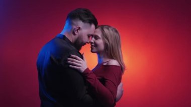 Good choice. Couple date. Neon light people. Confident flirting woman dancing with man showing ok gesture embracing on dark shadow red blue background.