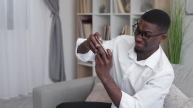 Office leisure. Mobile game. Employee fun. Happy excited man playing online on smartphone app enjoying work break on lobby couch.