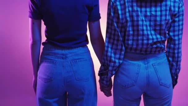 ゲイ関係だ ネオンライトの人々 女性カップル 認識できない2人の女性が手を取り 緑のバイオレットの背景にポーズを取ります — ストック動画