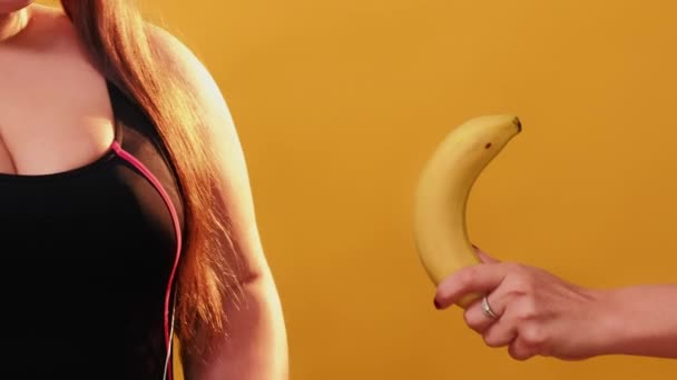 不健康な食べ物だ 体がポジティブだ 太りすぎの問題 幸せプラスサイズ女性選択ドーナツ代わりに提案バナナポーズ黄色の背景 — ストック動画