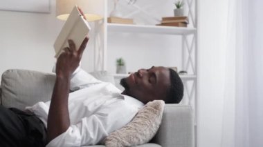 Reading relax. Businessman hobby. Domestic leisure. Cheerful concentrated man employee enjoying book resting on comfortable couch at home.