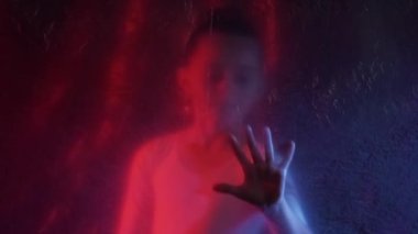 Children rights. Defocused silhouette. Kid protection. Red blue neon light sad trapped little girl hands touching wrinkled texture transparent polyethylene film on dark out of focus.