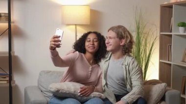 Mobile selfie. Beloved couple. Pleasant meeting. Happy man and woman embracing together making photo on smartphone in light room interior.