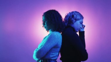 Couple quarrel. Problem relationship. Neon light portrait. Depressed man and woman posing back each other on green purple background.