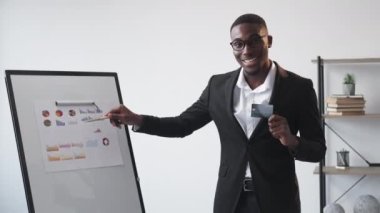 Business meeting. Financial service. Economy presentation. Joyful man bank advisor holding credit card coaching at whiteboard statistics graph.