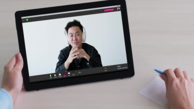 Video konferansı. Sanal görüşme. Çevrimiçi toplantı. Kulaklıklı neşeli adam dijital ofiste tablet kullanan kadın arkadaşla konuşuyor..