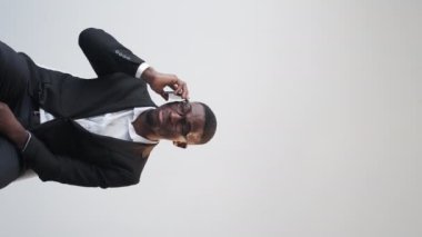 Vertical video. Bad connection. Confused man. Business problem. Annoyed male manager talking smartphone on white copy space background.