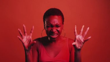 Anger hate. Horror threat. Frustration anxiety. Red neon color light scary furious woman frightening with hand claw gesture isolated on dark bright gif loop boomerang animation.