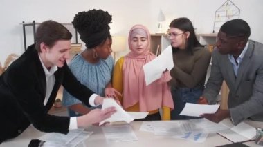 Annoying colleagues. Deadline work. Office pressure. Exhausted woman feeling frustrated while aggressive workers showing documents light room interior.