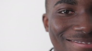 Detailed portrait. Man face. Happy feelings. Macro shooting of smiling happy male on white copy space studio background.